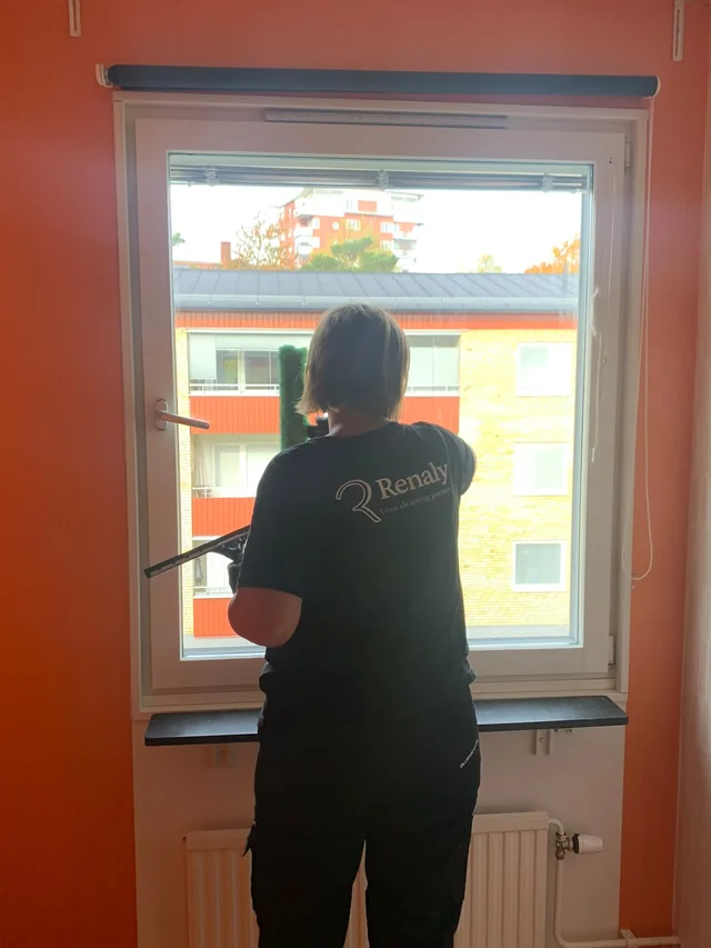 En medarbetare från Renaly putsar fönstret, sedd bakifrån