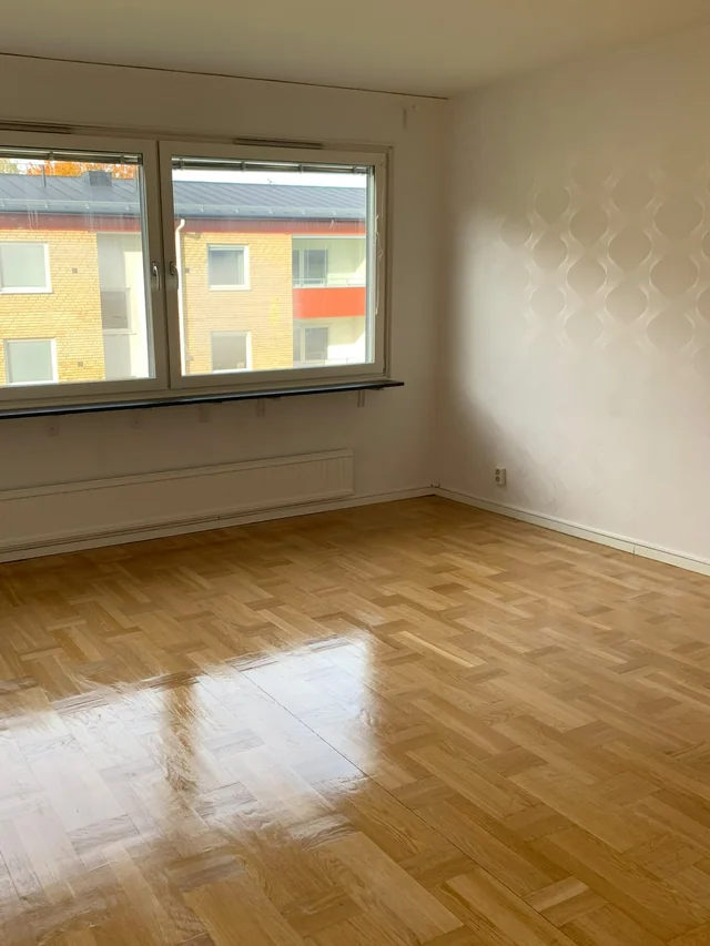 Tomt rum med parkettgolv och två fönster i bostaden i Hägersten