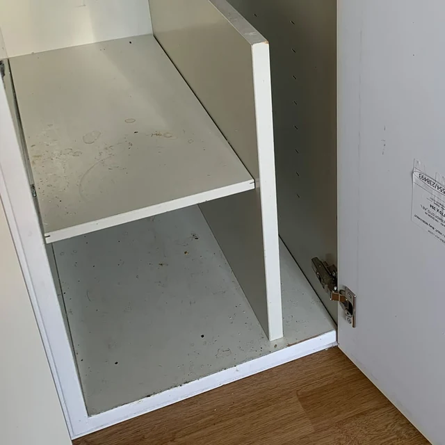 Köksskåpet före flyttstädningen, med fläckar på hyllan och skåpets botten