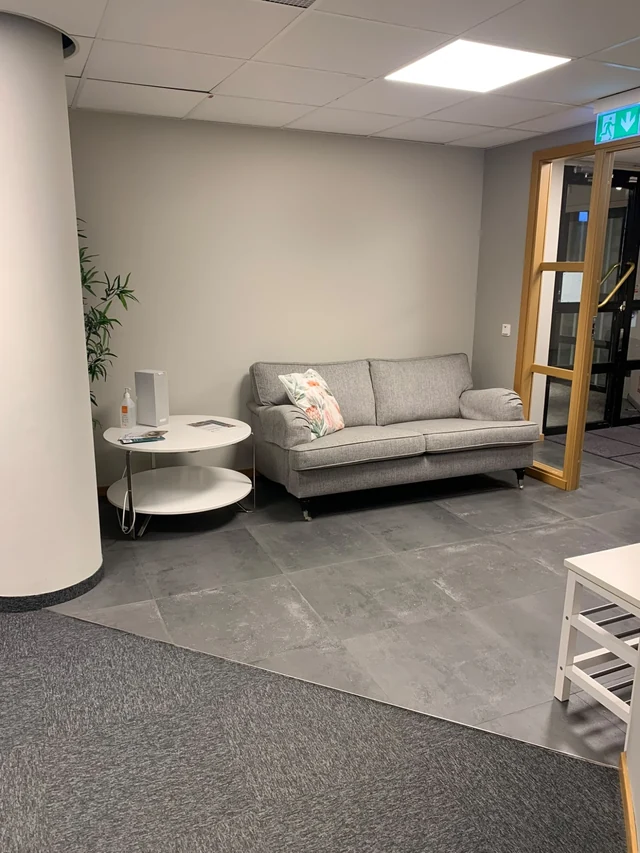 Entré med soffa, sidobord och stengolv på Novelias kontor