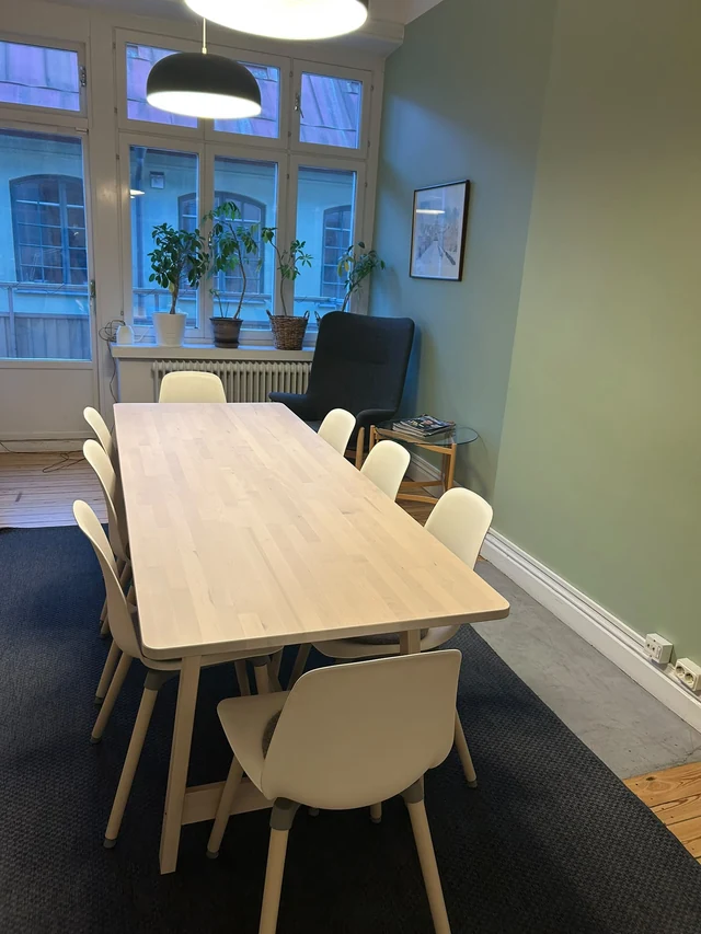 Ljust träbord och vita stolar vid fönstren på Sveriges förenade studentkårers kontor